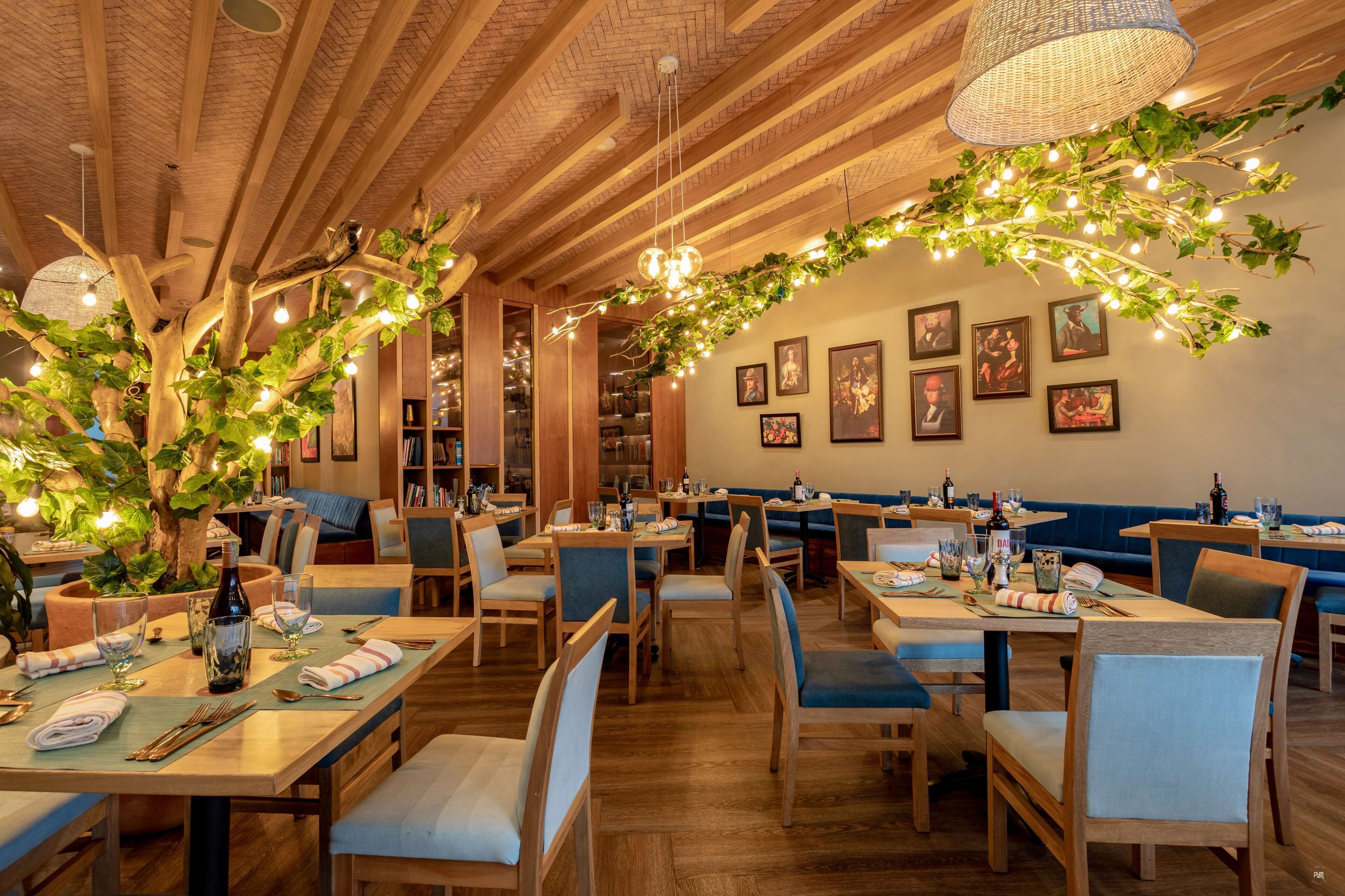 A restaurant with wooden tables, blue cushioned chairs, and a brick ceiling.