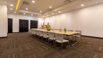 A conference room with a long table, multiple chairs, and a carpeted floor.