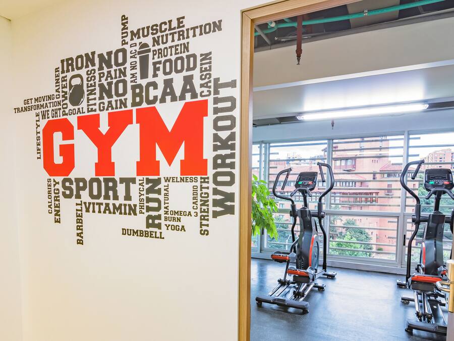 Een sportschool met een grote muurschildering met woorden over fitness en twee loopbanden in de ruimte.