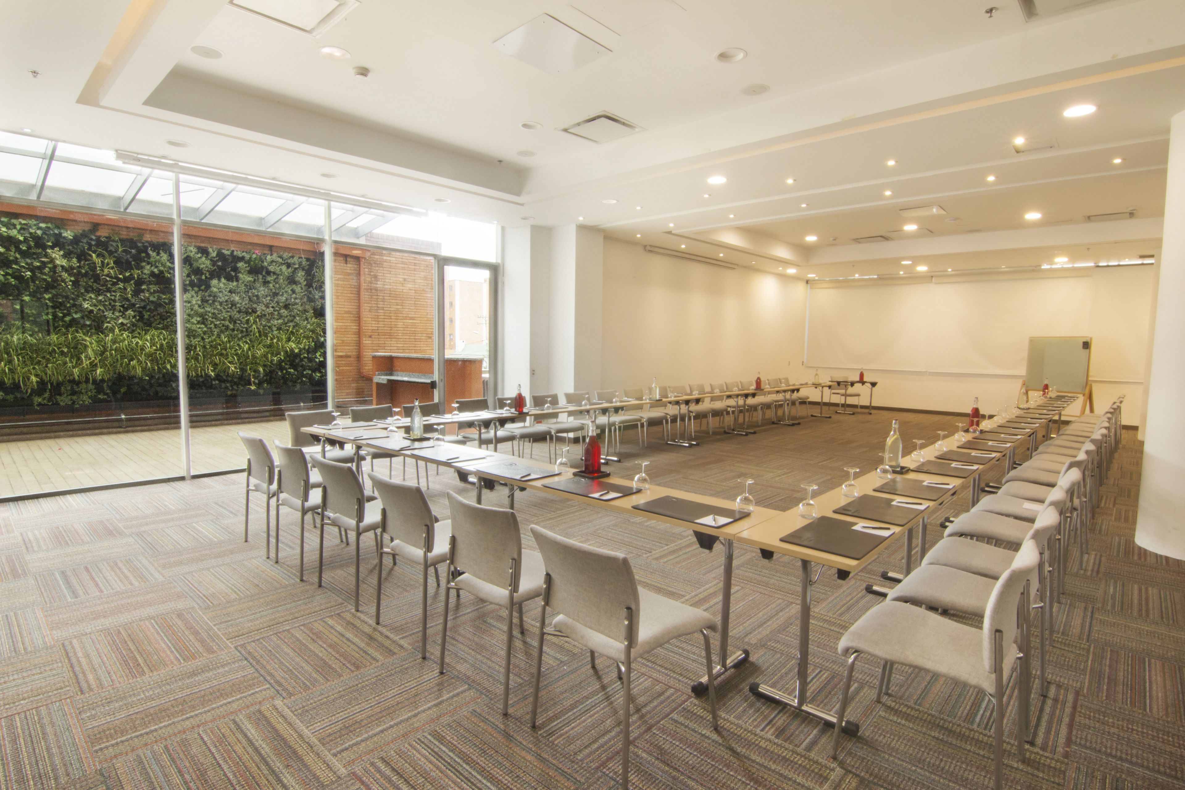 Uma sala de conferências com uma mesa comprida, cadeiras e um projetor.