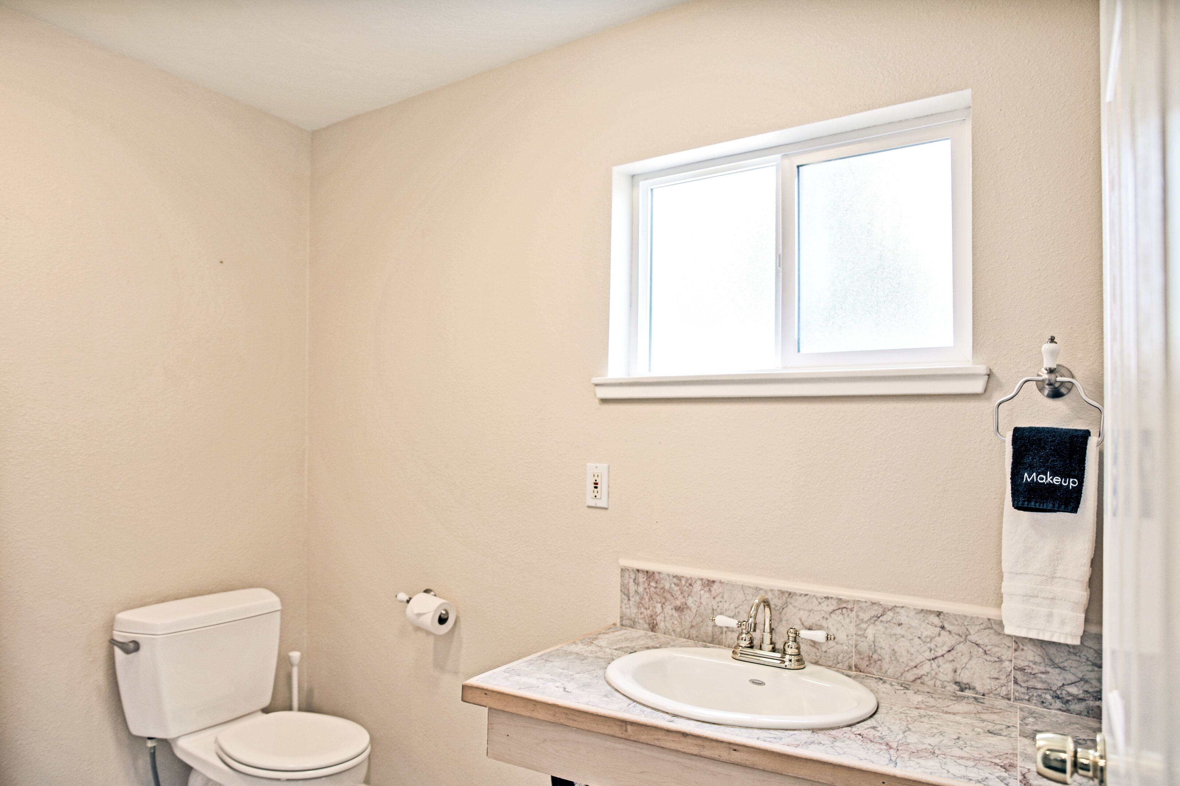 Un baño con inodoro, lavabo y ventana.