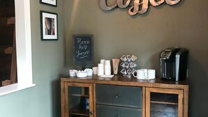 A room with a wooden cabinet, a coffee sign, framed pictures, and a chalkboard sign. - Sierra Mountain Inn (Grass Valley)