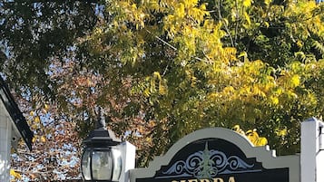 A sign for Sierra Mountain Inn with a white fence and trees in the background.