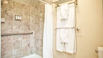 Ein Badezimmer mit Marmorwand, einer Badewanne, einer Duschvorhang und einem Handtuchhalter mit zwei Handtüchern.