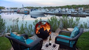 A marina with boats docked, a fire feature, and outdoor seating with a bottle and glasses. - Hyatt Place Long Island East End (Riverhead)
