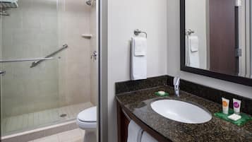 A bathroom with a glass-enclosed shower, a white sink, and a large mirror.