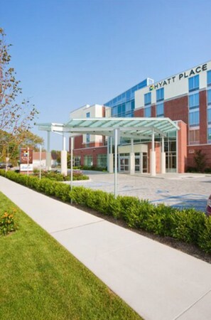 A modern hotel with a glass entrance canopy and a clear sky. - Hyatt Place Long Island East End (Riverhead)