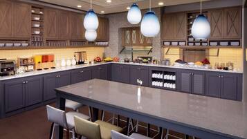 Una cocina moderna con armarios oscuros, una isla central e iluminación colgante.