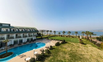 A hotel with a swimming pool, a tennis court, and a view of the sea.