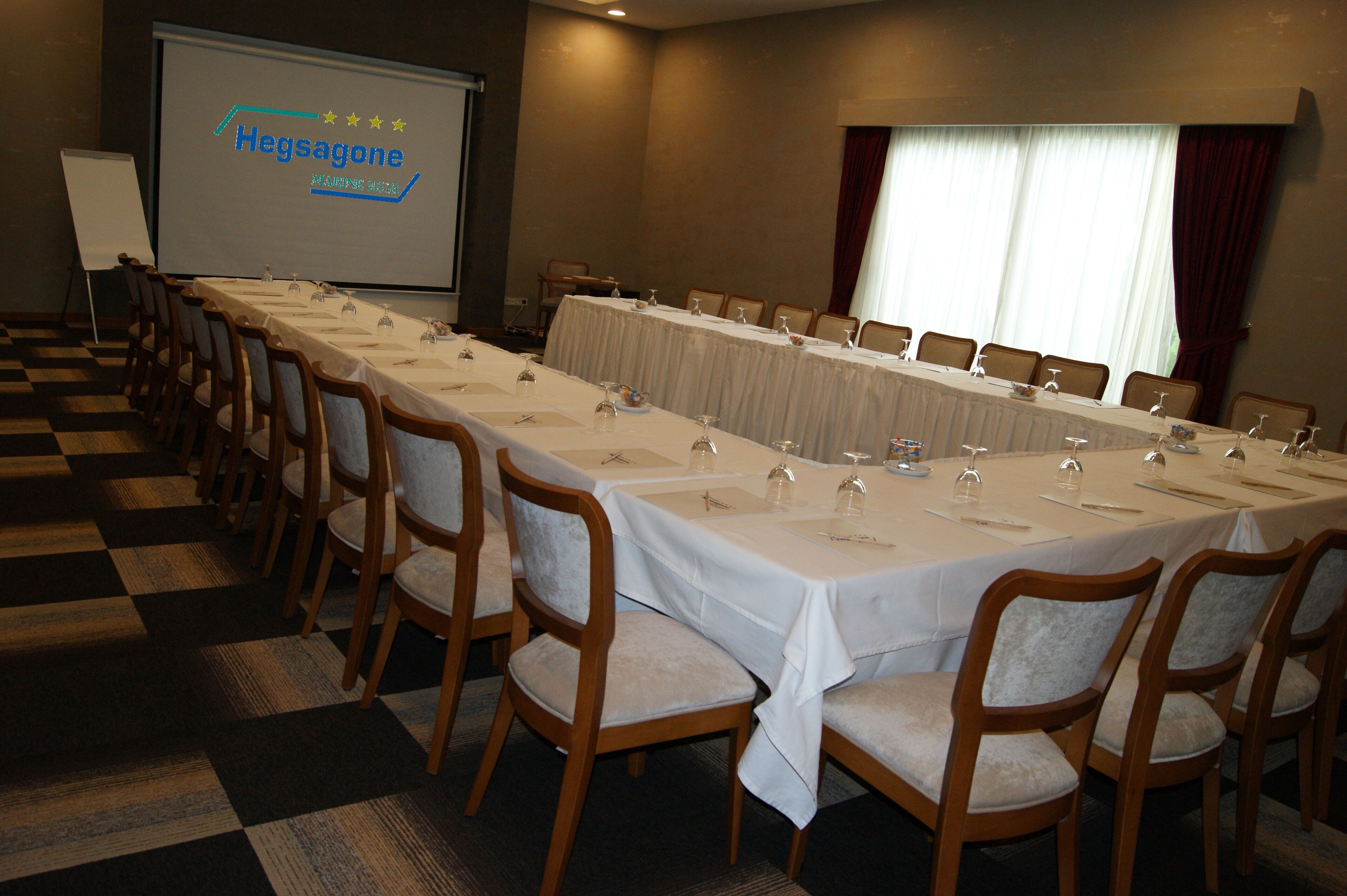 A conference room with a long table set for a meeting, equipped with microphones and glasses.