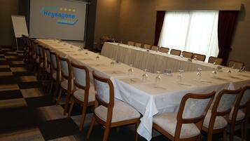 Un salón de conferencias con una larga mesa dispuesta para una reunión, equipado con micrófonos y vasos.