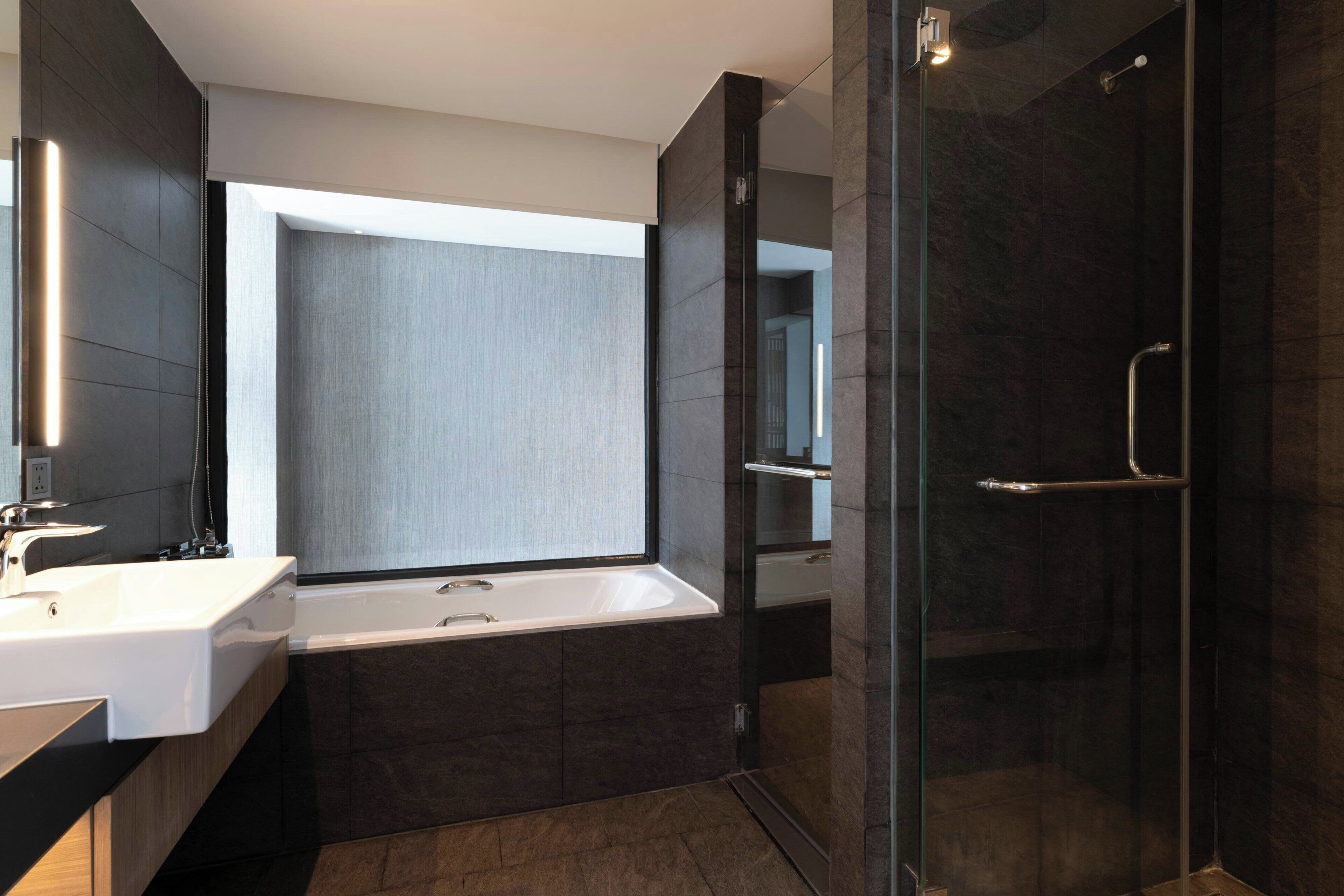 A modern bathroom with a bathtub, a glass shower enclosure, and a large mirror.