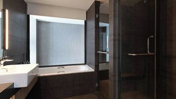 A modern bathroom with a bathtub, a glass shower enclosure, and a large mirror.