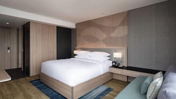A modern hotel room with a large bed, bedside tables, a desk, and a sofa.