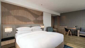 A modern hotel room with a large bed, bedside tables, a desk, and a chair.