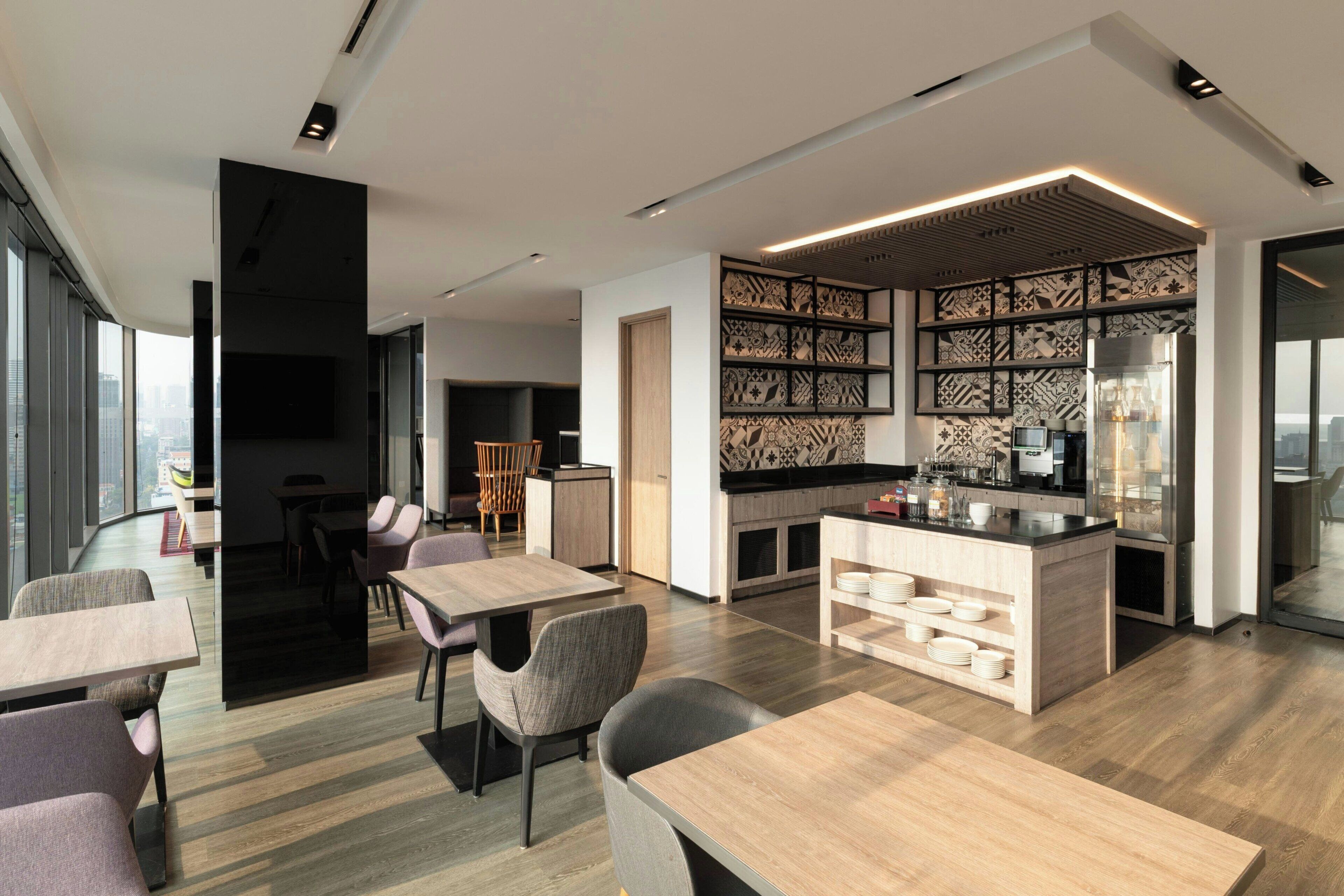 A modern kitchen with a central island, built-in shelving, and a dining area with tables and chairs.