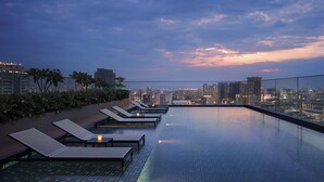 A rooftop infinity pool with lounge chairs and a cityscape view at dusk. - Courtyard by Marriott Phnom Penh (Phnom Penh)