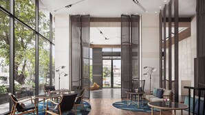 A modern interior with large windows, wooden flooring, and a seating area with tables and chairs. - Courtyard by Marriott Phnom Penh (Phnom Penh)