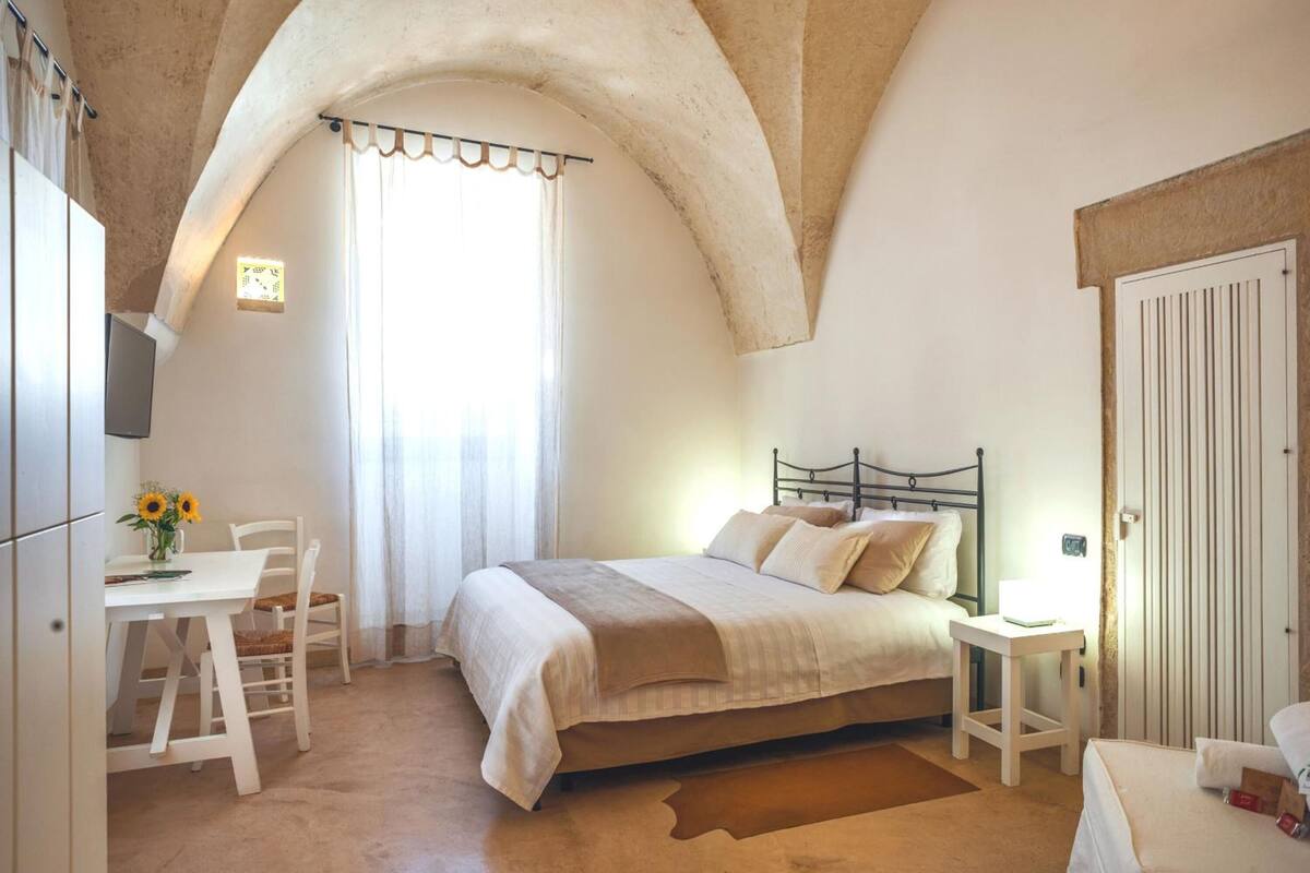 A bedroom with a bed, a desk, and a chair.