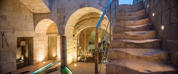 A stone interior with a spiral staircase and arched doorways. - Corte dei Francesi (Maglie)