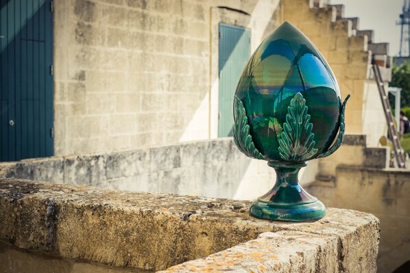 A green glass object on a stone ledge with a building in the background.