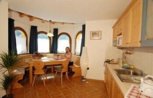 A cozy kitchen with a dining table, chairs, and a sink. - Gaia Wellness Residence Hotel (Mezzana)