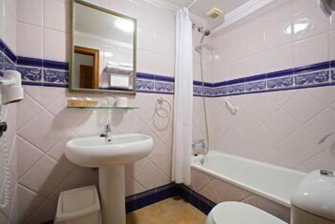 Een badkamer met een wastafel, spiegel, douche en toilet.