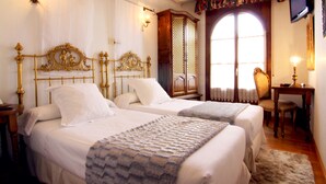 Habitació d'hotel amb dos llits, una televisió, un escriptori amb una cadira i una finestra amb cortines.
