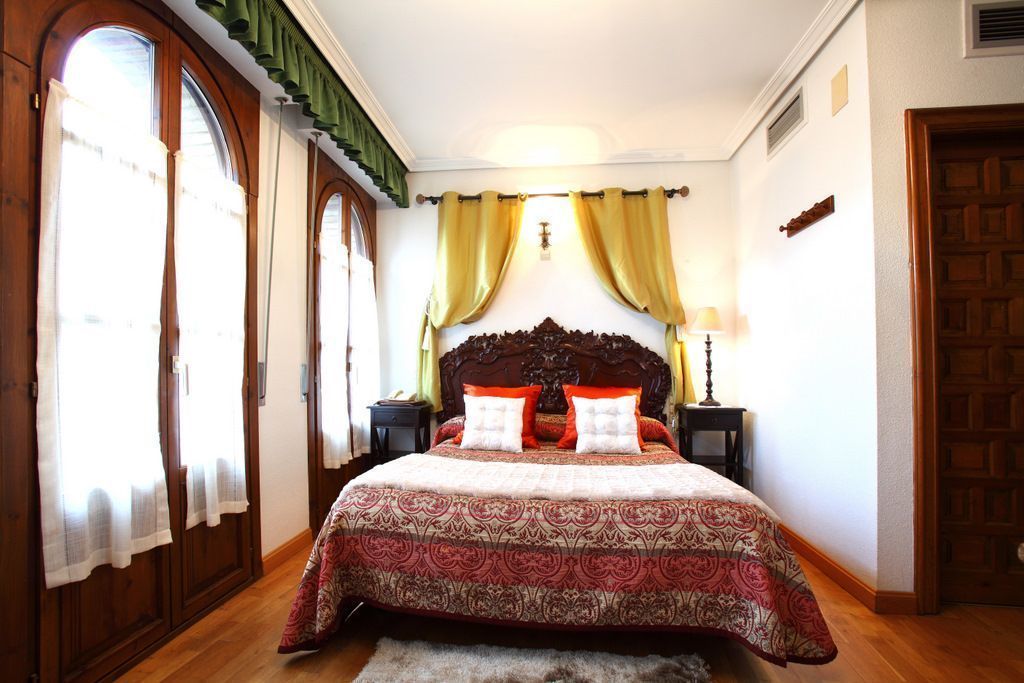 A bedroom with a large bed, wooden headboard, two bedside tables, and a nightstand.