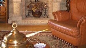 Un saló acollidor amb una llar de pedra, un sofà de pell i una televisió sobre un moble de fusta.