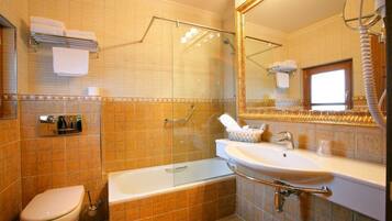 Un baño con ducha de vidrio, bañera, lavamanos e inodoro.
