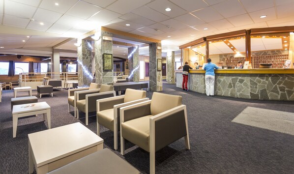 A hotel lobby with seating areas, a reception desk, and a stone accent wall.