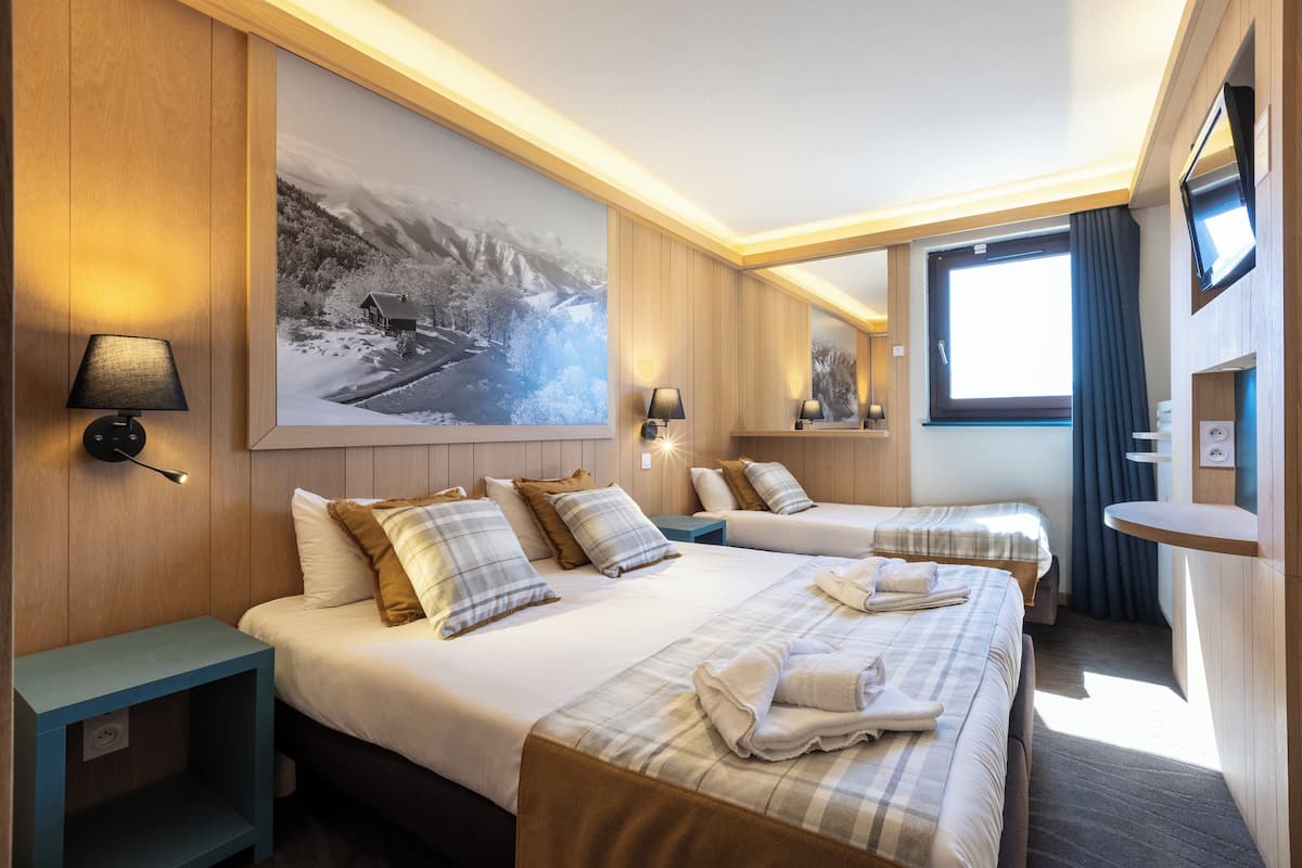 A hotel room with two beds, a large painting, a TV, and a small table.