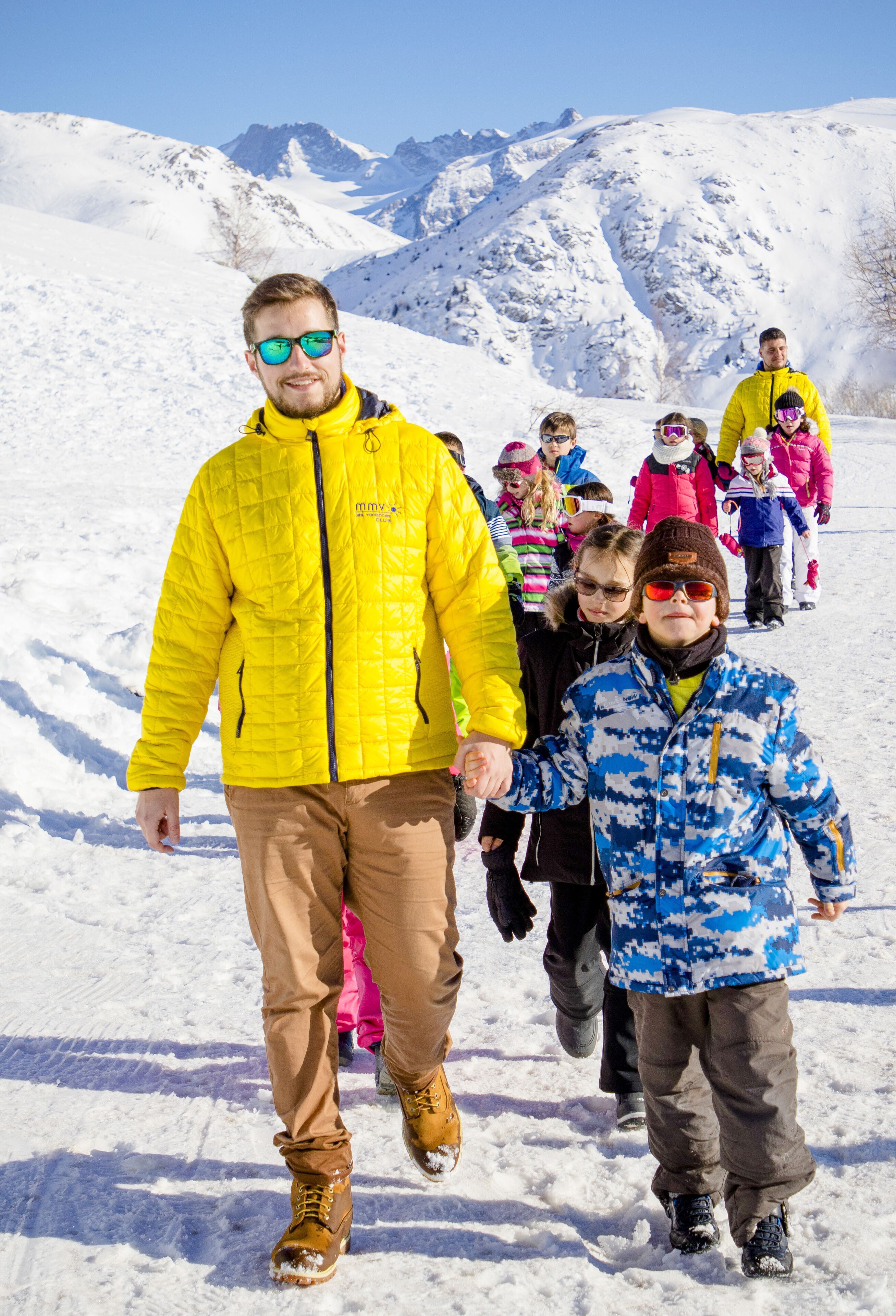 A snowy mountain landscape with a group of people walking.