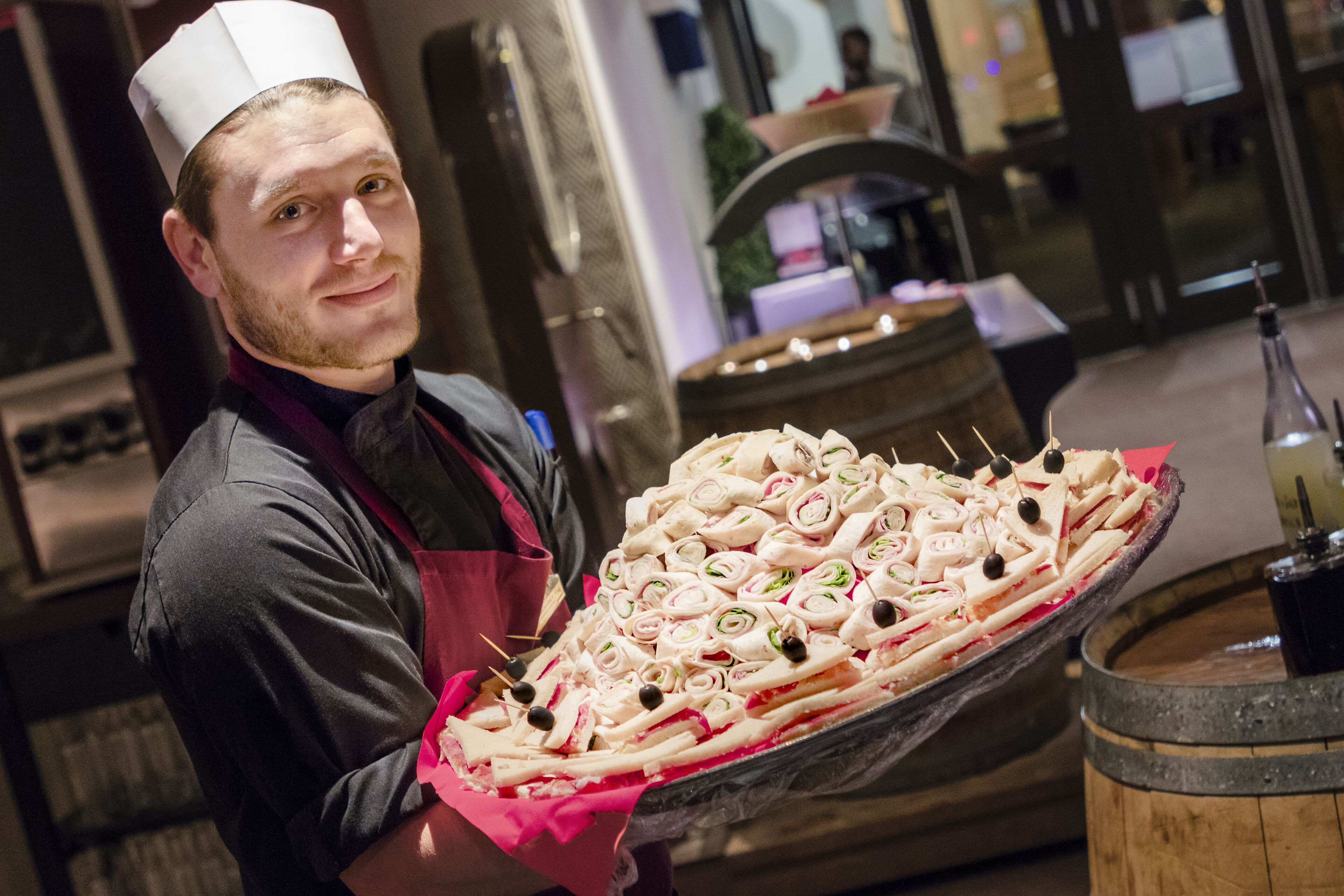 A chef holding a large tray of appetizers.