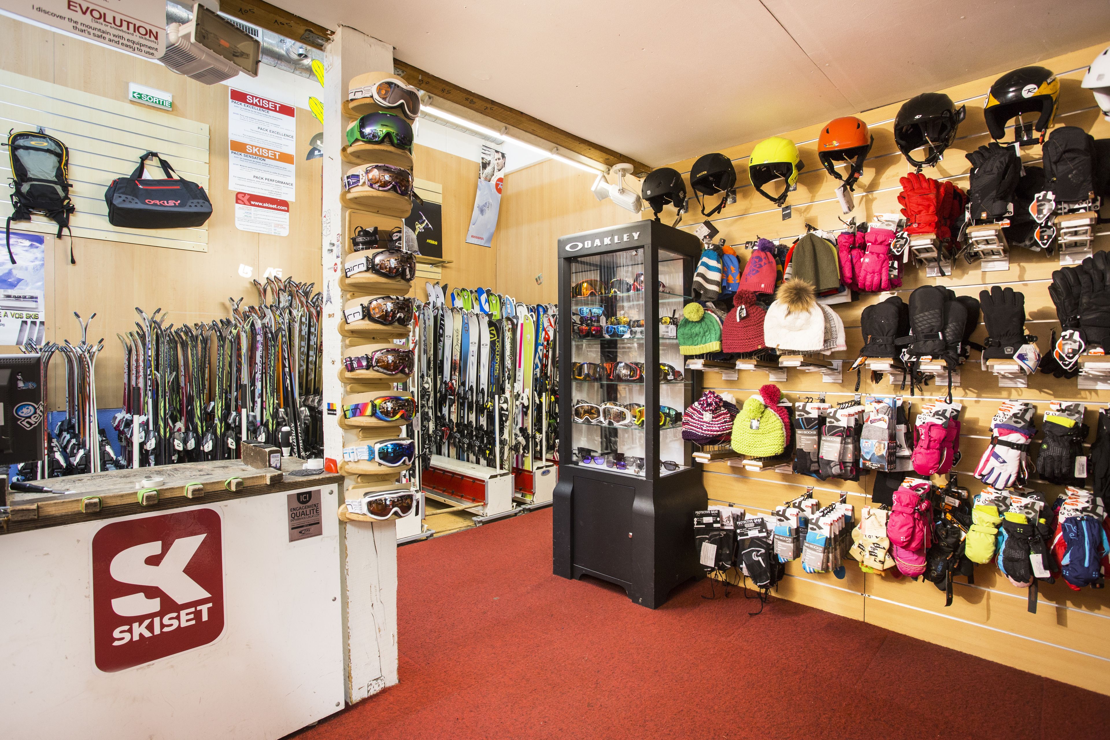 Un magasin d’articles de ski où l’on trouve des rangées de skis, de casques et de chaussures de ski.