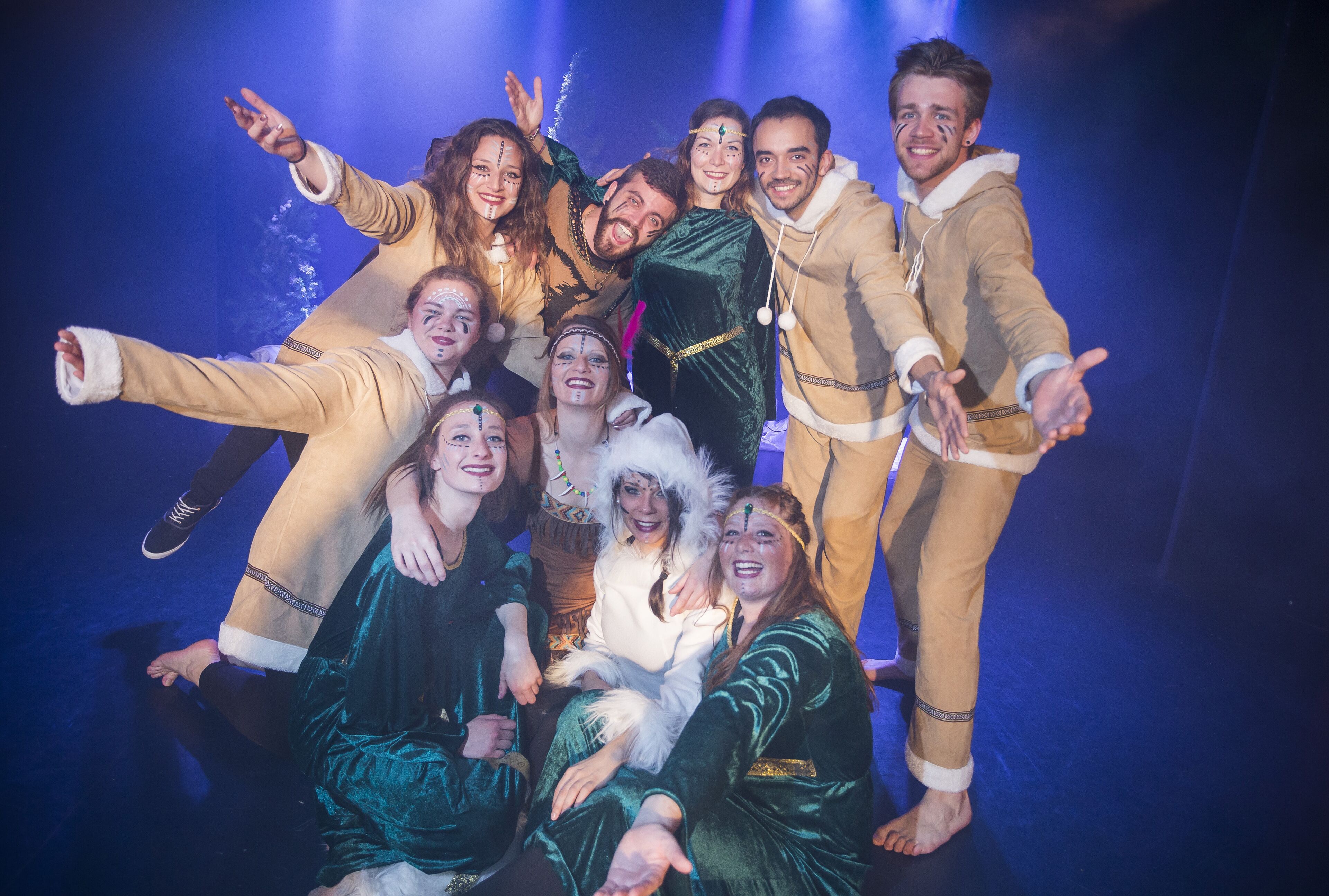 A group of people in costumes on a stage with a blue background.
