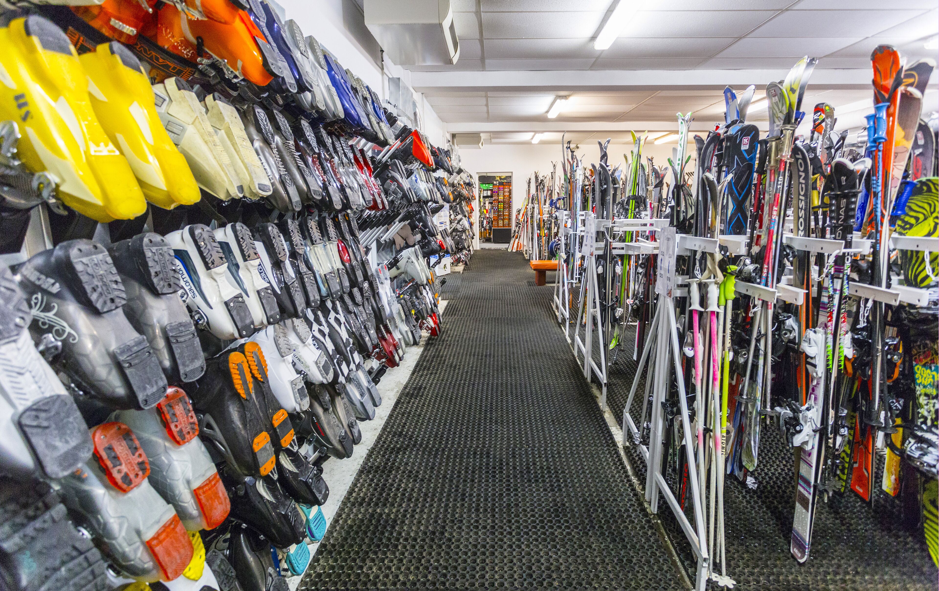 A ski equipment store with rows of skis and ski boots on display.