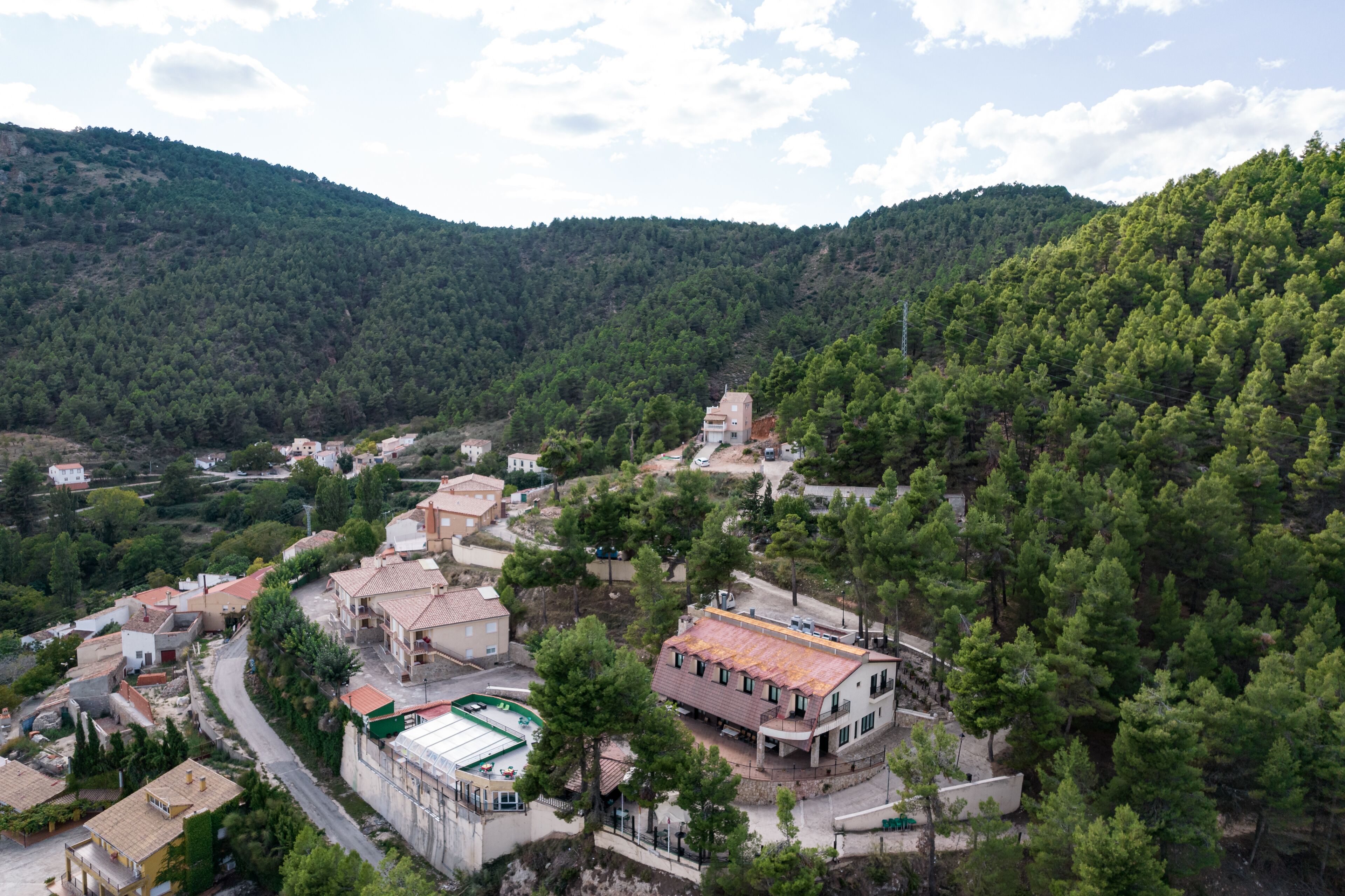 Un pequeño pueblo con arquitectura tradicional, rodeado de densos bosques y colinas.