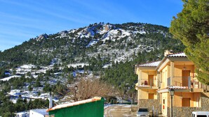 A mountain with snow-covered slopes and a building with a balcony. - Residencial Turístico Vega-Sierra (Bogarra)