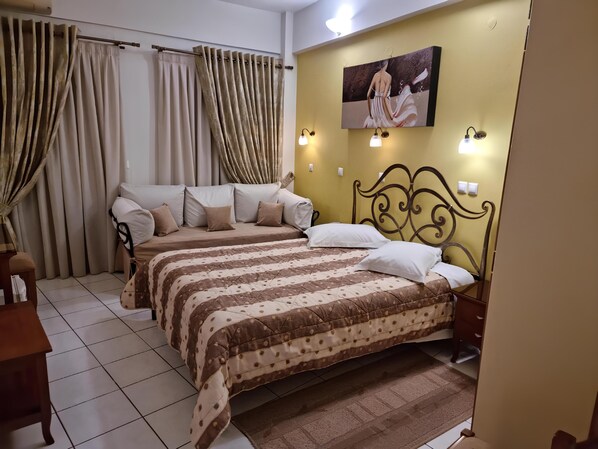 A bedroom with two beds, beige curtains, a painting on the wall, and wall-mounted lights.