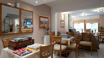A dining area with wooden chairs and tables, a large mirror, and a television on the wall.