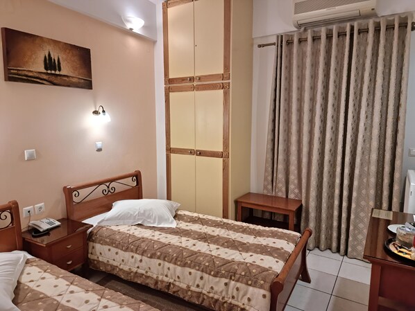 Un dormitorio con dos camas, un armario de madera, una mesita de noche con un teléfono y un cuadro en la pared.