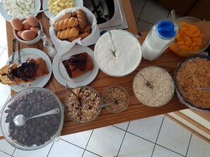 A breakfast buffet with various food items including eggs, bread, cereal, and pastries.