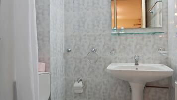 Un baño con inodoro, lavamanos y cortina de ducha.
