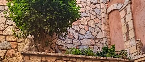 A stone wall with a potted plant and a small fountain.