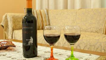 Een fles Merlot wijn en twee glazen op een tafel met een tafelkleed met dessin.