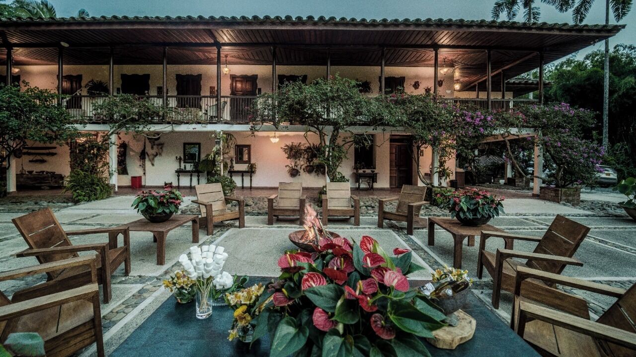 Un espace extérieur aménagé, abrité et doté de mobilier en bois et de plantes en pot.