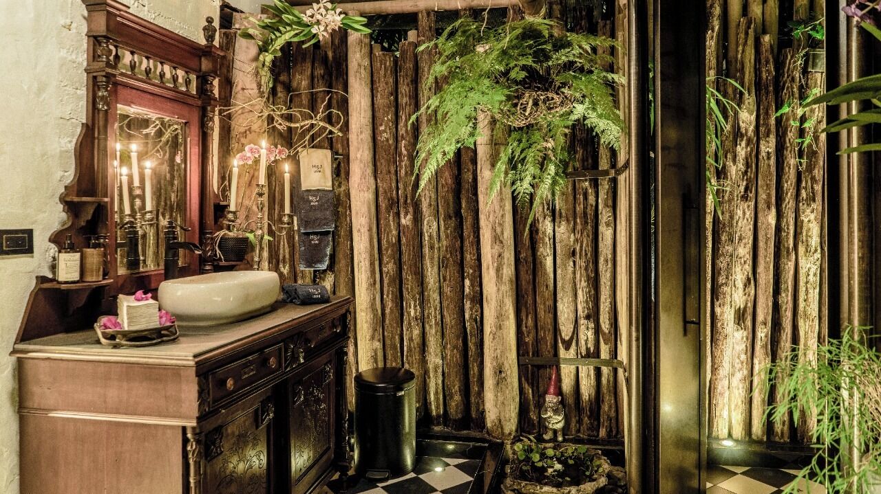 Ein Badezimmer im Vintage-Stil mit einem Holzwaschtisch, einem Spiegel, einem Waschbecken und einer hängenden Farne.