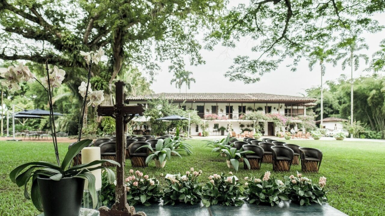 Un espace extérieur aménagé avec des chaises et des tables, entouré de verdure et avec un bâtiment en arrière-plan.